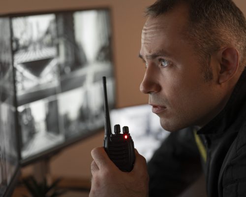 retrato-guarda-de-seguranca-masculino-com-estacao-de-radio-e-telas-de-camera (1)